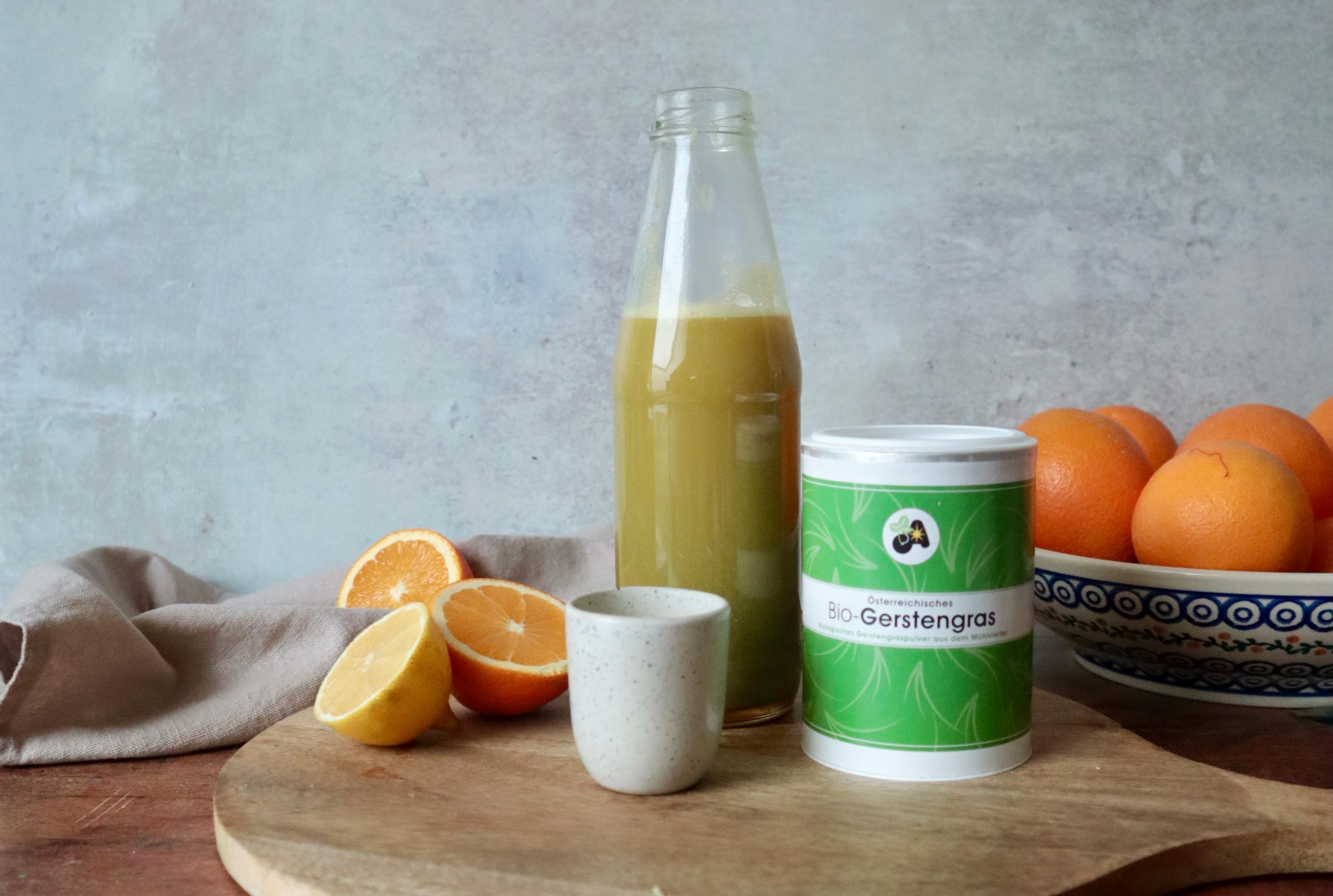 Bio-Gerstengras Saft und Orangen auf einem Holztisch